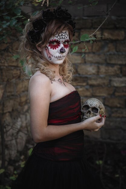 Closeup retrato de Calavera Catrina Mujer joven con maquillaje de calavera de azúcar Dia de los muertos Día de los Muertos Halloween en el bosque con calavera