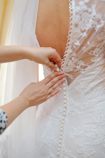Closeup retrato de una dama de honor ayudando a la novia con su vestido