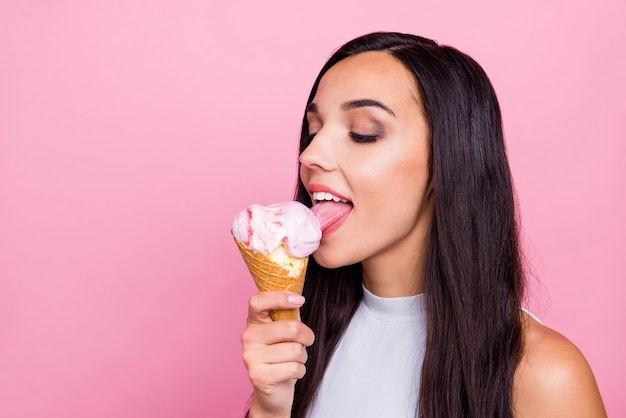 Closeup retrato de dama lamiendo helado aislado sobre pared rosa