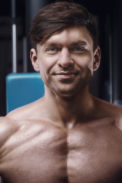 Foto closeup retrato de um homem atlético bonito no ginásio. fisiculturista forte com peito e ombros musculosos na academia. conceito de fitness e esporte