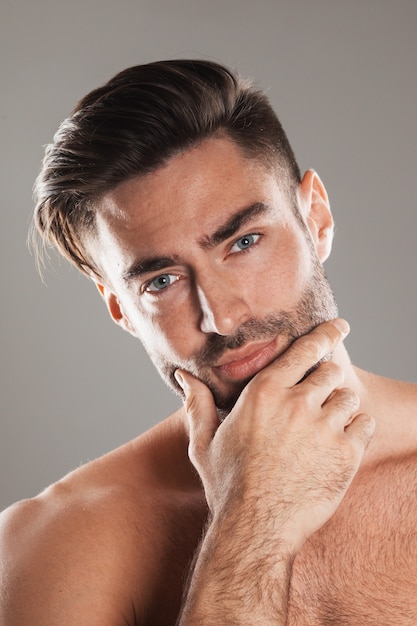 Foto closeup retrato de um lindo modelo masculino, homem branco com cabelo escuro e olhos cinzentos segurando o queixo