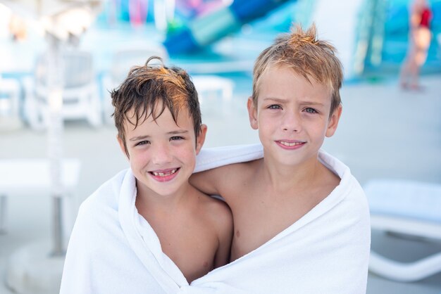 Closeup retrato de um menino sorridente enrolado em uma toalha depois de nadar na piscina externa
