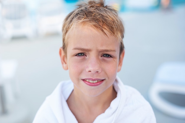 Closeup retrato de um menino sorridente enrolado em uma toalha depois de nadar na piscina externa