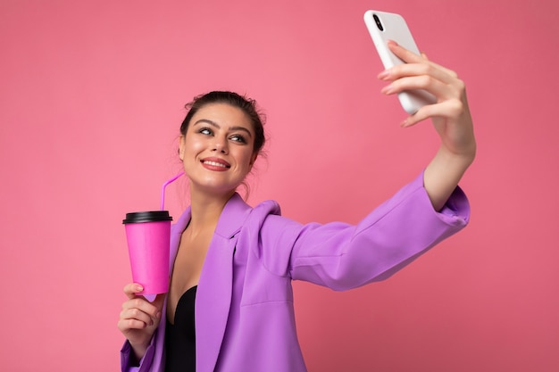 Closeup retrato de uma bela jovem morena sorridente em um elegante terno roxo em uma rosa