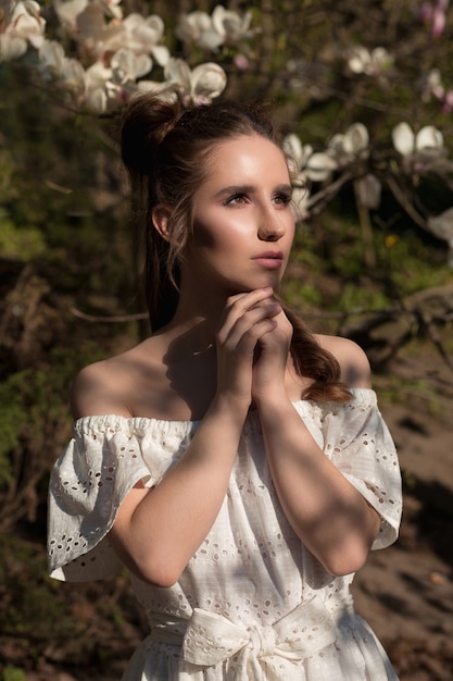 Closeup retrato de uma linda mulher morena em um jardim de magnólia em flor