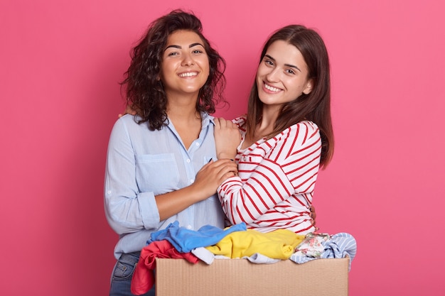 Closeup retrato de dos niñas emocionadas con caja de cartón llena de ropa para uso secundario