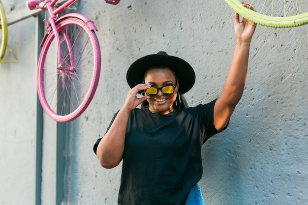 Closeup retrato elegante jovem afro-americana com cabelos cacheados em óculos de sol da moda em urbano com espaço de cópia e lugar para publicidade de fotos de verão hipster com estilo instagram