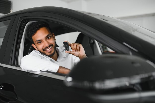 Closeup retrato feliz sonriente joven comprador mostrando las llaves de su coche nuevo