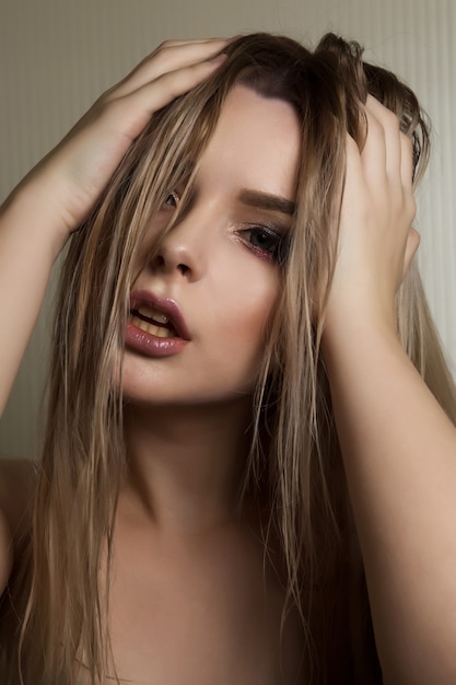 Closeup retrato de glamorosa modelo rubia con maquillaje profesional y cabello mojado