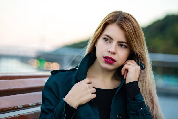 Closeup retrato de gloriosa mujer joven con labios rojos posando en la ciudad. Espacio para texto