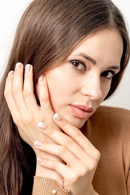 Closeup retrato de hermosa joven morena con tocar su cabello con los dedos cuidados