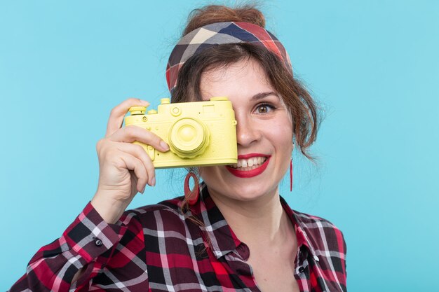 Closeup retrato de una hermosa joven positiva con una camisa a cuadros tomando fotografías con un