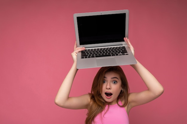 Closeup retrato de hermosa joven sorprendida diciendo wow con la boca abierta sosteniendo la computadora netbook