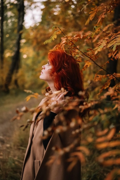 Closeup retrato de una hermosa mujer de otoño de pie cerca de coloridas hojas de otoño