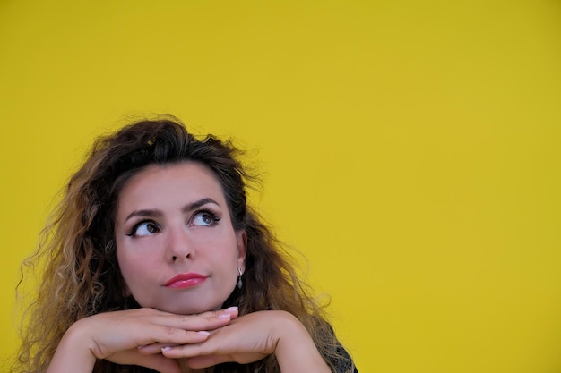 Closeup retrato de una hermosa niña sobre un fondo amarillo mujer muestra consideración emociones humanas