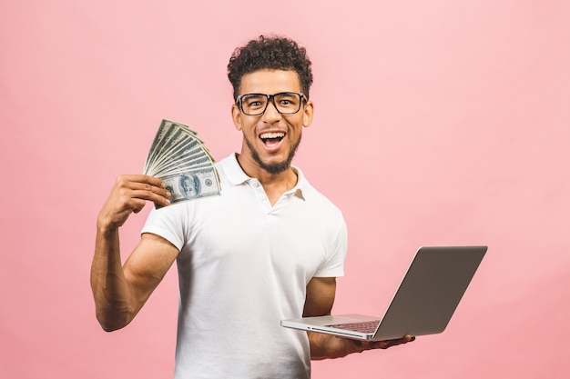 Foto closeup retrato, jovem empresário de sucesso americano africano ganhando dinheiro com a internet, segurando dinheiro na mão, laptop em outra