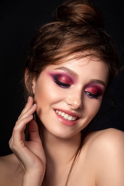 Closeup retrato de joven bella mujer sonriente con maquillaje de verano moderno de ojos ahumados rosa brillante