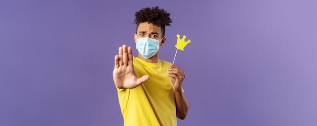 Closeup retrato de joven hipster chico en máscara médica estirar la mano adelante parada gesto sosteniendo smal