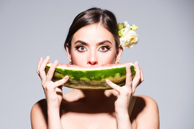 Closeup retrato de joven mujer hispana o italiana sensual comiendo sandía aislado en backg gris