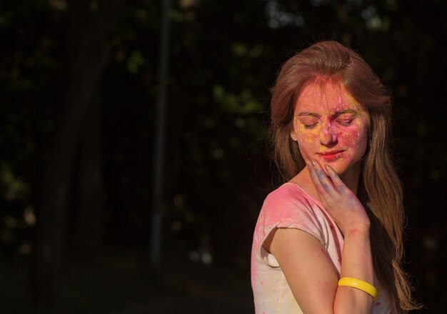 Closeup retrato de modelo bonita morena cubierta con polvo de colores, posando en el festival de Holi