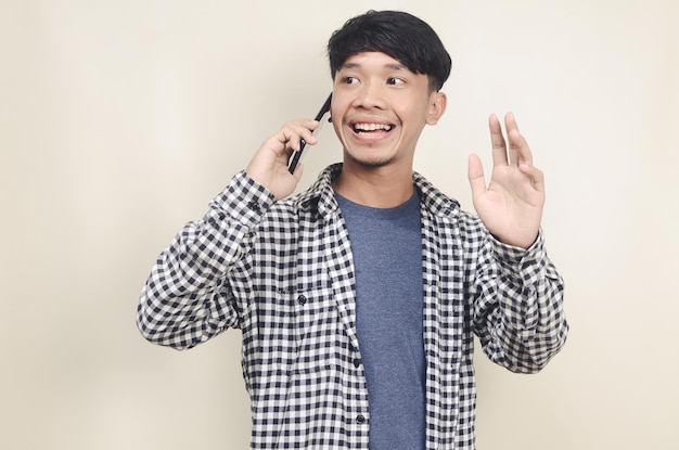 Closeup retrato de modelo masculino asiático joven feliz vistiendo camisa a cuadros hablando por teléfono