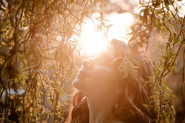 Closeup retrato de mujer adulta cerca del árbol al atardecer