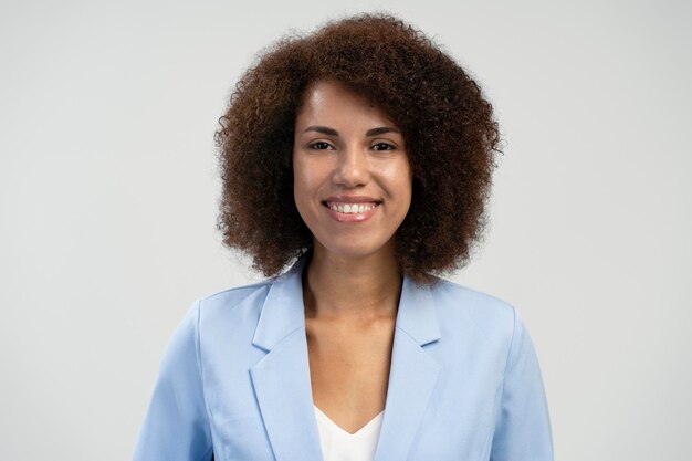 Closeup retrato mujer bonita afroamericana sonriendo mirando a la cámara aislada fondo azul