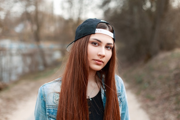 Closeup retrato de una mujer joven y bonita con una gorra de béisbol negra y una chaqueta vaquera