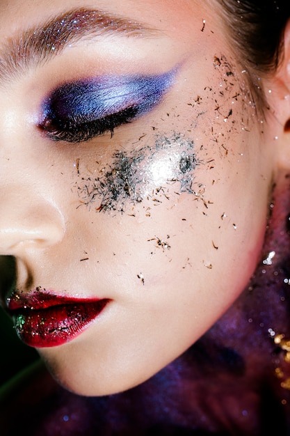 Closeup retrato de mujer con maquillaje de ojos ahumados y destellos.