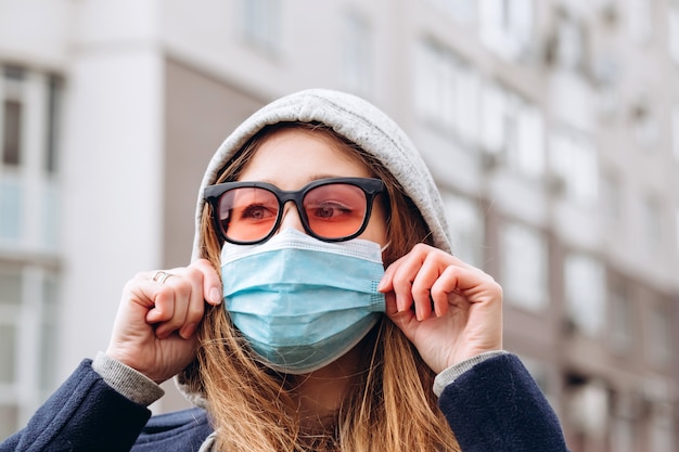 Closeup retrato de una mujer con una máscara médica en la calle, epidemia de un coronavirus. La mujer violó las reglas del autoaislamiento. SARS-CoV-2. protégete de COVID-19.