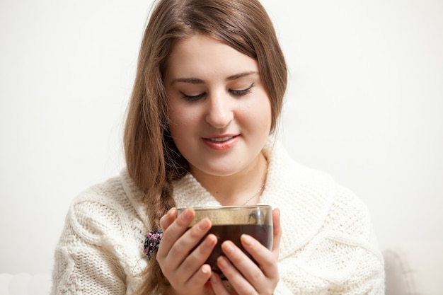 Closeup retrato de mujer morena en suéter blanco sosteniendo una taza de té