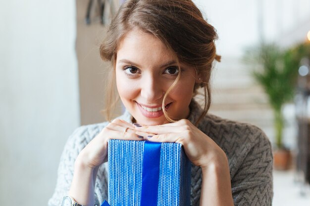 Closeup retrato de una mujer sonriente con caja de regalo mirando a la cámara