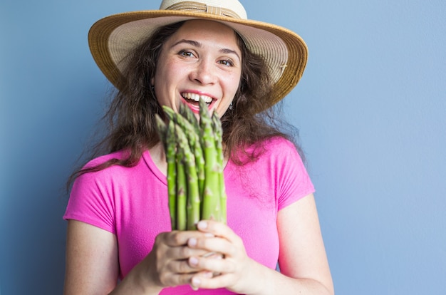 Closeup retrato de mujer sorprendida divertida sostiene espárragos delante de su cara