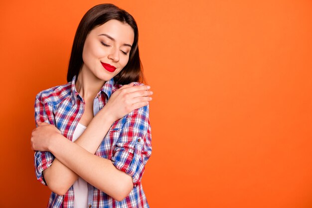 Foto closeup retrato de niña con camisa de cuadros abrazándose a sí misma