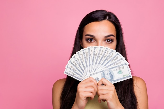 Closeup retrato de niña cara de cierre con un ventilador de dinero aislado sobre pared rosa