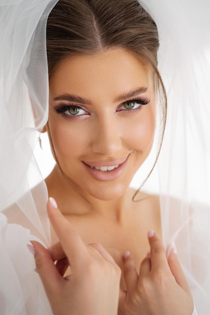 Closeup retrato de una niña en un vestido de novia y un velo en la cabeza una mirada amorosa a la cámara ojos verdes y cabello castaño