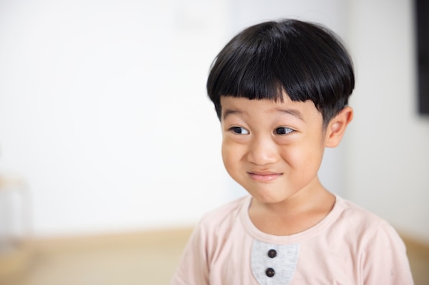 Closeup retrato niño asiático pelo negro recto vistiendo una camisa marrón claro mirando a la cámara