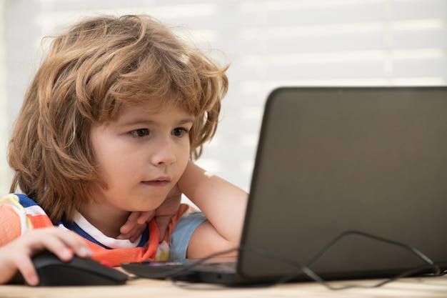 Closeup retrato de niño de escuela mirando la computadora portátil durante la lección. Educación a distancia.