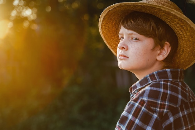 Closeup retrato de un niño en un sombrero de paja en la luz del atardecer