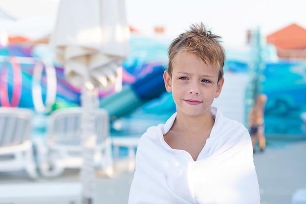 Closeup retrato de un niño sonriente envuelto en una toalla después de nadar en la piscina al aire libre