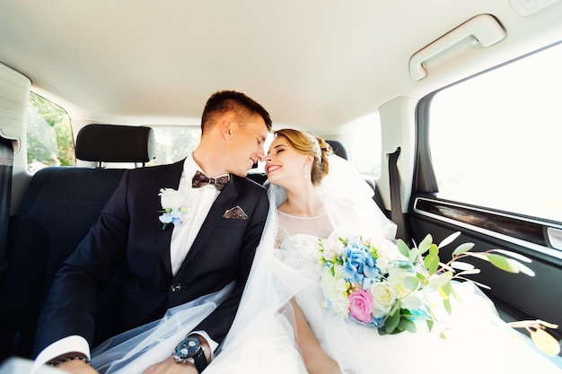 Closeup retrato de recién casados besándose en el asiento trasero de un coche