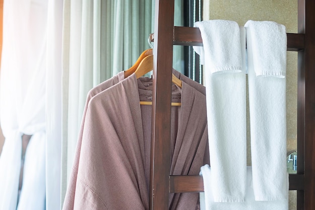 Closeup roupão limpo e toalha pendurada no guarda-roupa de madeira no hotel de luxo. Relaxe e viaje o conceito