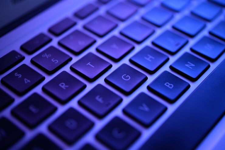 CloseUp Shot de un teclado azul brillante bajo bajo la luz baja hacking concepto de malware de violación de seguridad