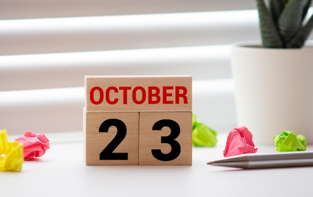 Foto closeup surface white wooden calendar with black 23 october word on blurred brown wood desk