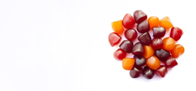 Closeup textura de gomitas multivitamínicas rojas, naranjas y púrpuras sobre fondo blanco estilo de vida saludable