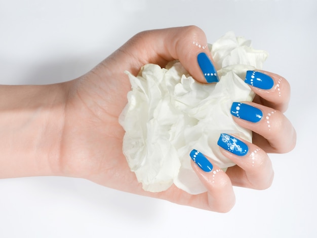 Closeup tiro da mão de uma mulher com manicure de inverno azul em fundo branco