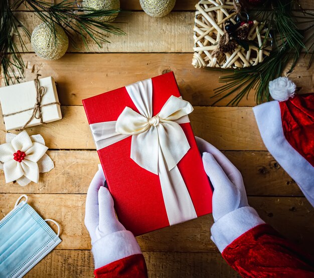 Closeup tiro das mãos do Pai Natal com luvas brancas a segurar um presente de Natal