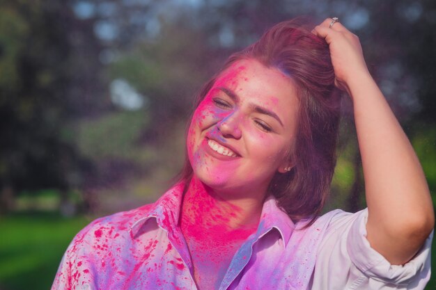 Closeup tiro de alegre mulher caucasiana de olhos fechados celebrando o Festival Holi