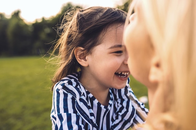 Closeup tiro de filha linda menina feliz abraçando sua mãe no parque mãe sorridente amorosa e filha rindo passam tempo juntos no parque maternidade feliz pessoas e emoção