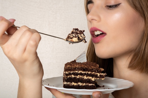 Foto closeup tiro de jovem modelo com maquiagem natural, desfrutando de bolo de chocolate doce. espaço para texto